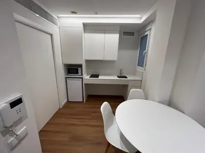 a white kitchen with a white table and chairs at Old Town Flats Casa del Bisbe in Valencia