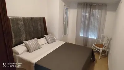 a bedroom with a bed and a window and a chair at TU CASA en Benetússer , VALENCIA in Benetúser