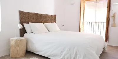 a bedroom with a large white bed with a wooden headboard at Casa El Olmo de Navajas in Navajas