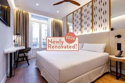 a hotel room with a bed and a sign that reads fully renovated at Petit Palace Plaza de la Reina in Valencia