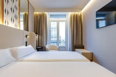 a hotel room with two beds and a window at Petit Palace Plaza de la Reina in Valencia