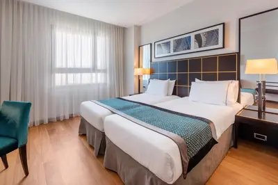 a bedroom with a large bed and a green chair at Eurostars Gran Valencia in Valencia