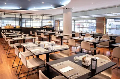 a restaurant with tables and chairs and windows at Eurostars Acteón in Valencia