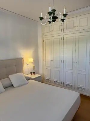 a white bedroom with a large bed and a chandelier at Agradable Villa junto al mar con piscina in Sagunto