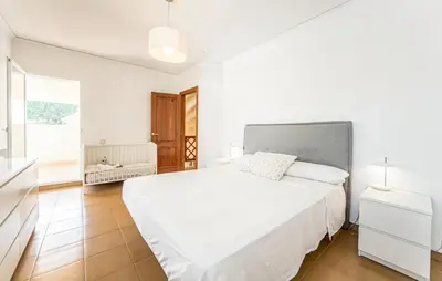 a white bedroom with a large bed and a window at Agradable Villa junto al mar con piscina in Sagunto