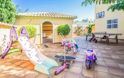 a patio with play equipment and a ping pong table at Agradable Villa junto al mar con piscina in Sagunto