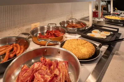 a buffet with many different types of food in pans at Catalonia Excelsior in Valencia