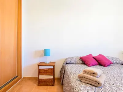 a bedroom with a bed with pink pillows and a table at Apartment Las Dunas by Interhome in Moncófar