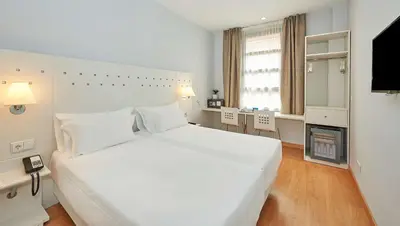 a white bedroom with a large bed and a television at NH Valencia Las Ciencias in Valencia