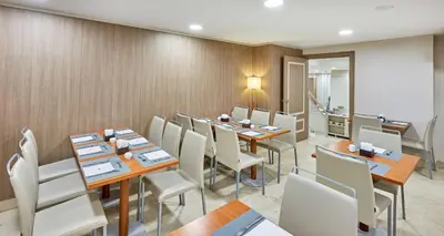a dining room with tables and white chairs at NH Valencia Las Ciencias in Valencia