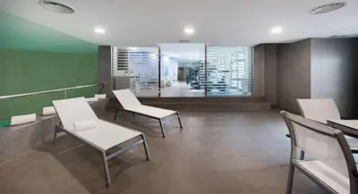 a waiting room with white chairs and a mirror at NH Valencia Las Artes in Valencia