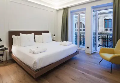 a bedroom with a large white bed and a yellow chair at One Shot Reina Victoria in Valencia
