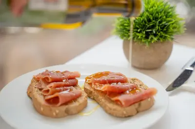 a white plate with two pieces of bread with tomatoes on it at Hotel RH Sorolla Centro in Valencia