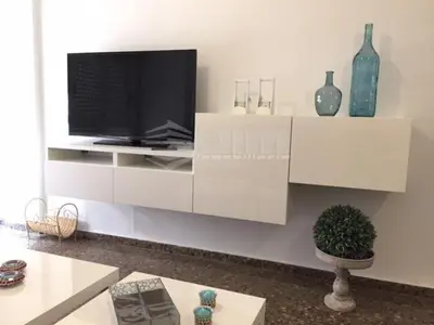 a living room with a tv on a white cabinet at UIM Mediterraneo Claveles Wifi in Puerto de Sagunto