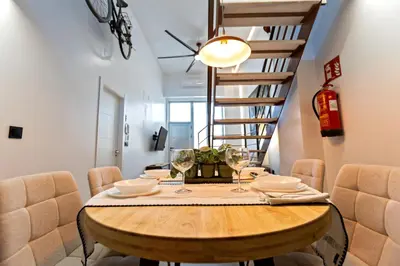 a dining room with a wooden table and a spiral staircase at Loft Nou Benicalap - Housevanlive in Valencia