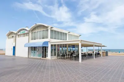 a building with tables and chairs in front of the beach at Malvarrosa Las Arenas II in Valencia