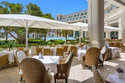 a restaurant with white tables and chairs and umbrellas at Las Arenas Balneario Resort in Valencia