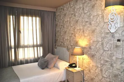 a bedroom with a stone wall with a bed and a lamp at Vincci Lys in Valencia