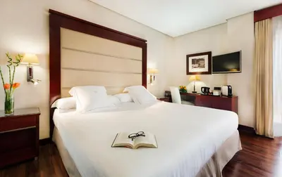 a bedroom with a large white bed with a book on it at Hotel Valencia Center in Valencia
