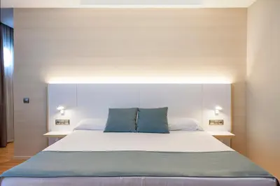 a bedroom with a large bed with two blue pillows at Hotel Olympia Valencia in Alboraya