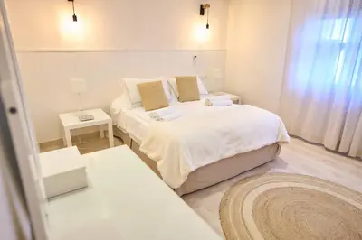 a white bedroom with two beds and two tables at El Oasis Villa Resort in La Eliana
