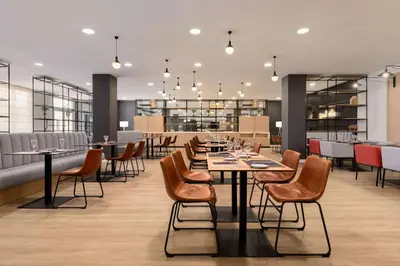 a restaurant with tables and chairs and a bar at Ramada by Wyndham Valencia Almussafes in Almussafes