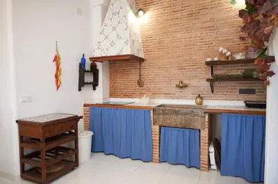 a kitchen with blue cabinets and a brick wall at El mas allà in Chulilla