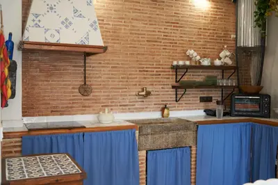 a kitchen with blue curtains and a brick wall at El mas allà in Chulilla