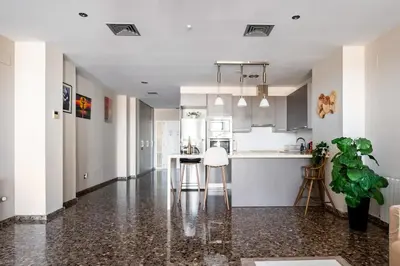 a white kitchen with a counter and a table at Moderno apartamento con vistas al mar en Valencia in Valencia