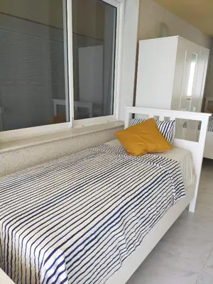 a white bed with a yellow pillow sitting next to a window at Florazar 3 in Cullera