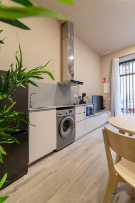 a kitchen with a washing machine and a table at Art Lofts Gardens in Valencia