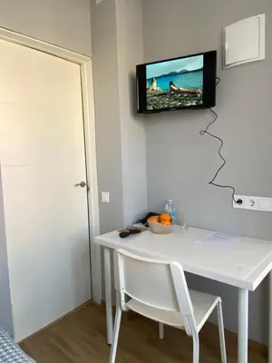 a room with a white table and a tv on the wall at Hostal Orange Vibes in Paterna