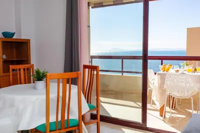 a room with a table and chairs and a balcony at Florazar Apartment Cullera Beachfront in Cullera