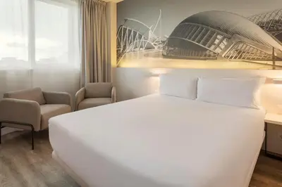 a hotel room with a white bed and a chair at B&B HOTEL Valencia Arena in Valencia