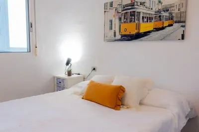 a bedroom with a white bed with a yellow pillow at The Beach Apartment in El Puig
