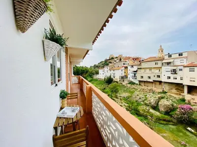 a balcony with two chairs and a view of a city at Las Peñetas in Bolbaite