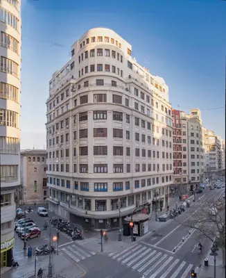 a large white building on a city street with cars at Hotel Mediterraneo Valencia in Valencia