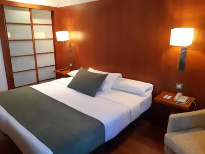 a hotel room with a bed with a phone and a chair at Hotel Xon's Valencia in Aldaya
