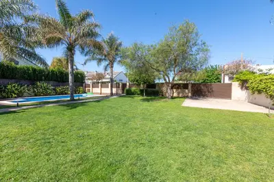 a yard with a swimming pool and palm trees at Casa junto al mar con jardín in Sagunto