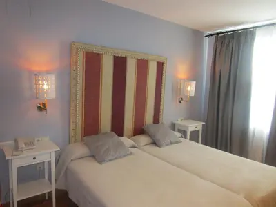 a bedroom with a bed with two tables and two lamps at Hotel Patilla Ciudad de Requena in Requena