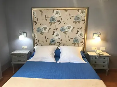 a bedroom with a blue bed with a floral headboard at Hotel Patilla Ciudad de Requena in Requena