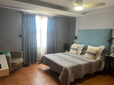 a bedroom with a bed and a chair and a window at Hotel Patilla Ciudad de Requena in Requena