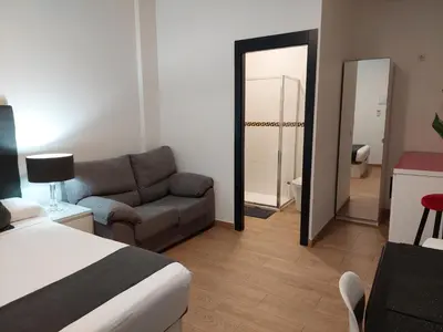 a room with a bed and a couch and a mirror at Apartamentos Rous - Solo adultos in Valencia