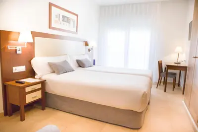 a hotel room with a large bed and a table at Aparthotel Albufera in Alfafar
