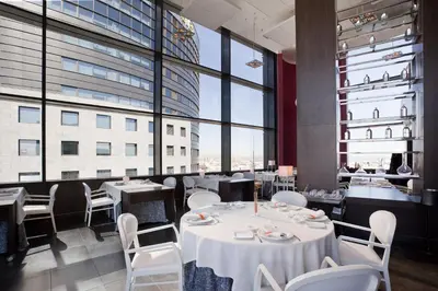 a restaurant with white tables and chairs and large windows at Ilunion Aqua 4 in Valencia