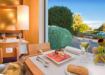 a table with a plate of food and a glass of wine at Flag Hotel Valencia in Masalfasar