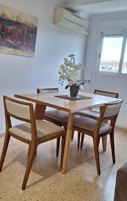 a wooden table with chairs and a vase of flowers on it at Gracioso apartamento en Massanassa in Benetúser