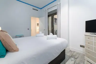a white bedroom with a large bed and a tv at ApartUP Patacona Azzure in Valencia