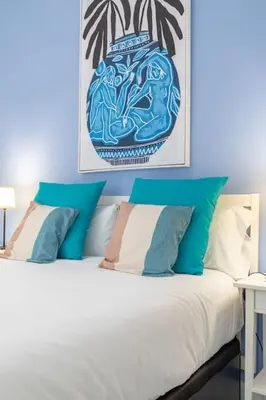 a bedroom with a bed with blue and white pillows at ApartUP Patacona Azzure in Valencia