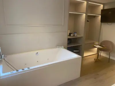 a large white bath tub in a room with a chair at YOU & CO. J. Botánico Boutique in Valencia